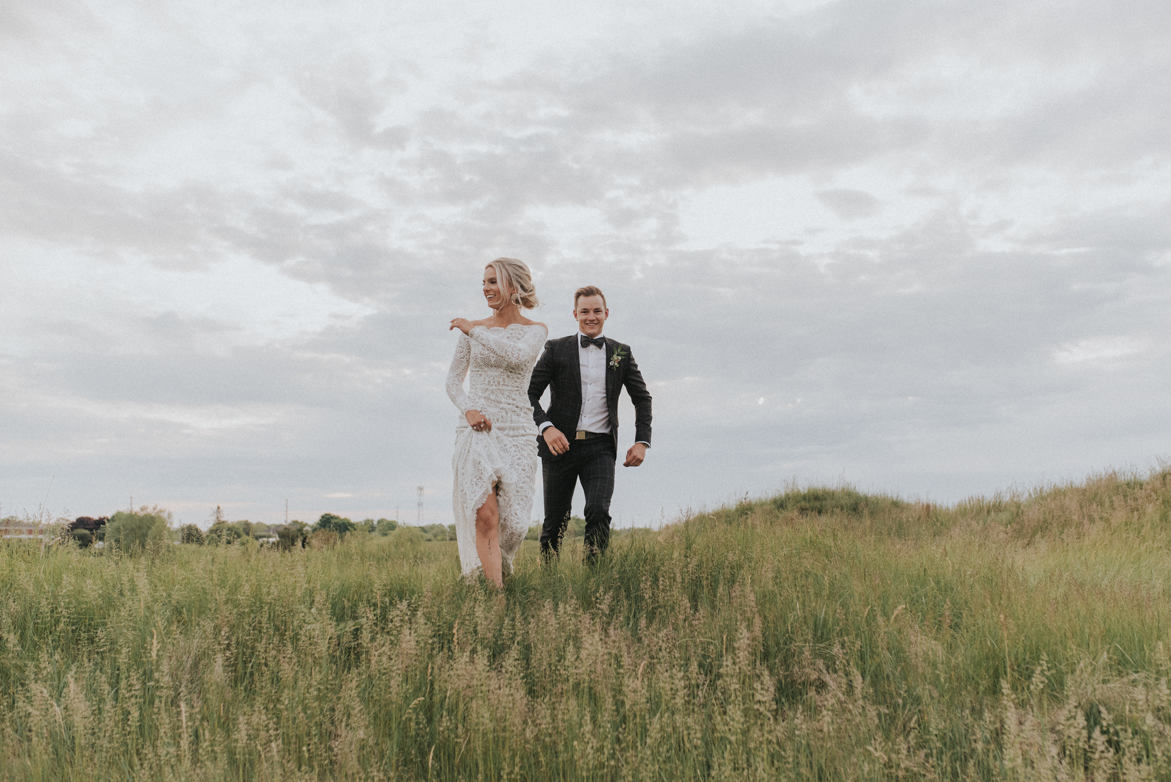 Spring Wedding at Piper's Heath Golf Club with Bride and Groom running through the tall grass.