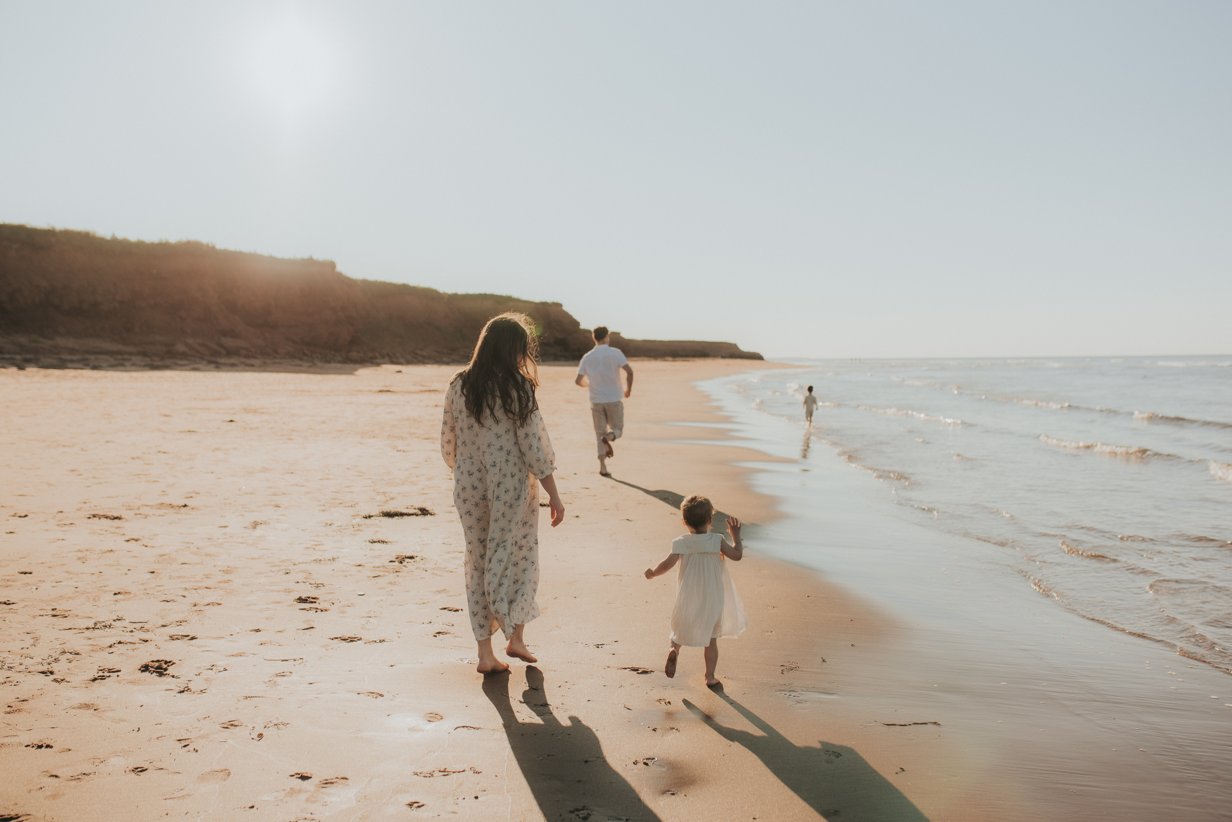 Family runs along the shore of a PEI beach.